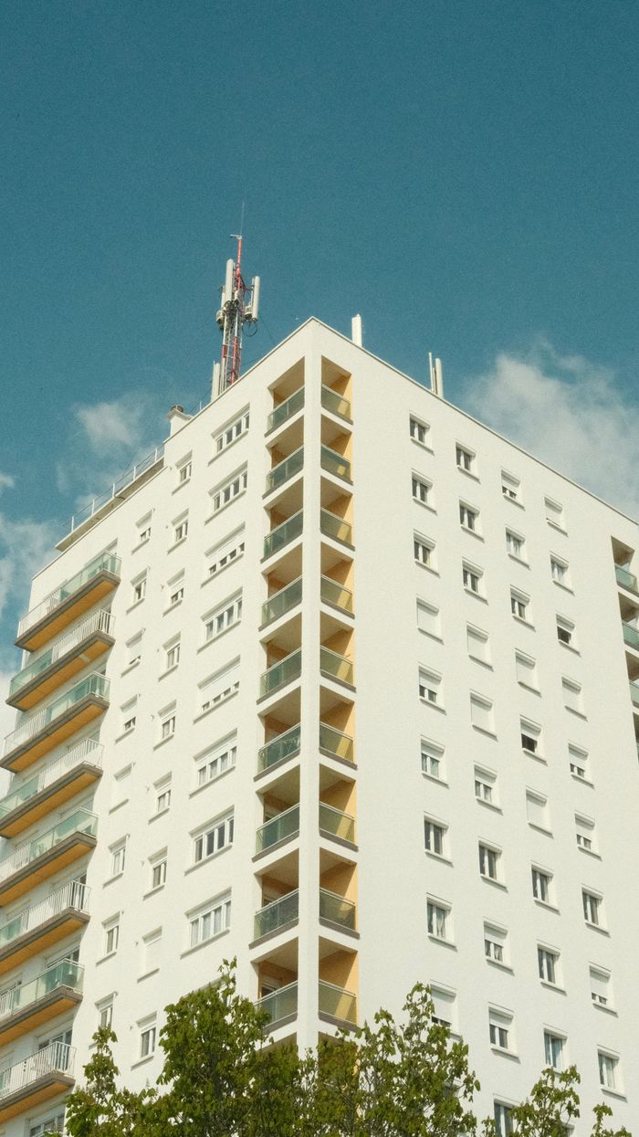 The Art of Drawing Readers In: Your attractive post title goes here Vertical shot of a sunlit urban apartment building with blue sky background.