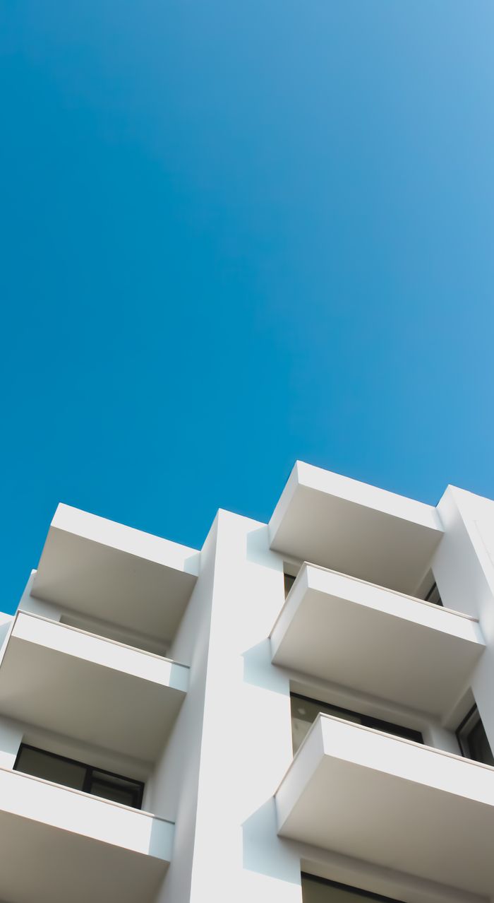 Crafting Captivating Headlines: Your awesome post title goes here Low angle shot of a modern white building with balconies against a clear blue sky, showcasing architectural design.